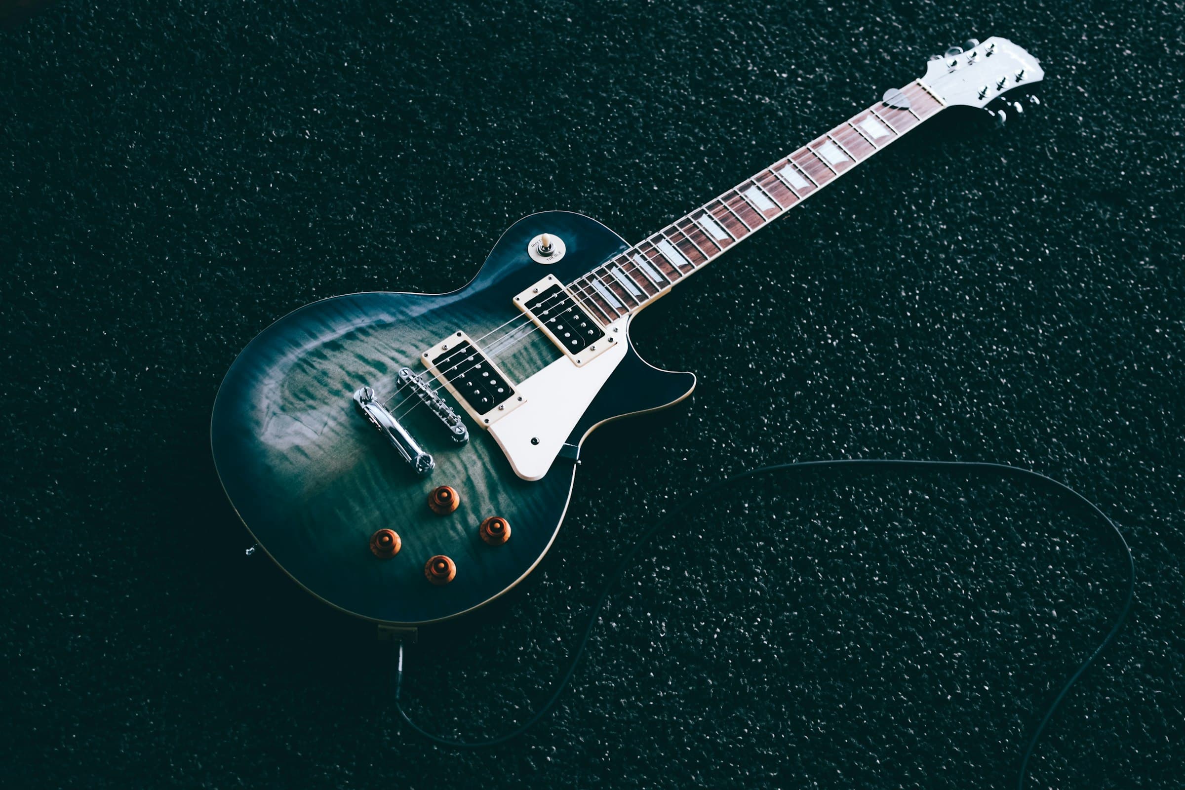 A shiny flame-top Pro Tones electric guitar in low light